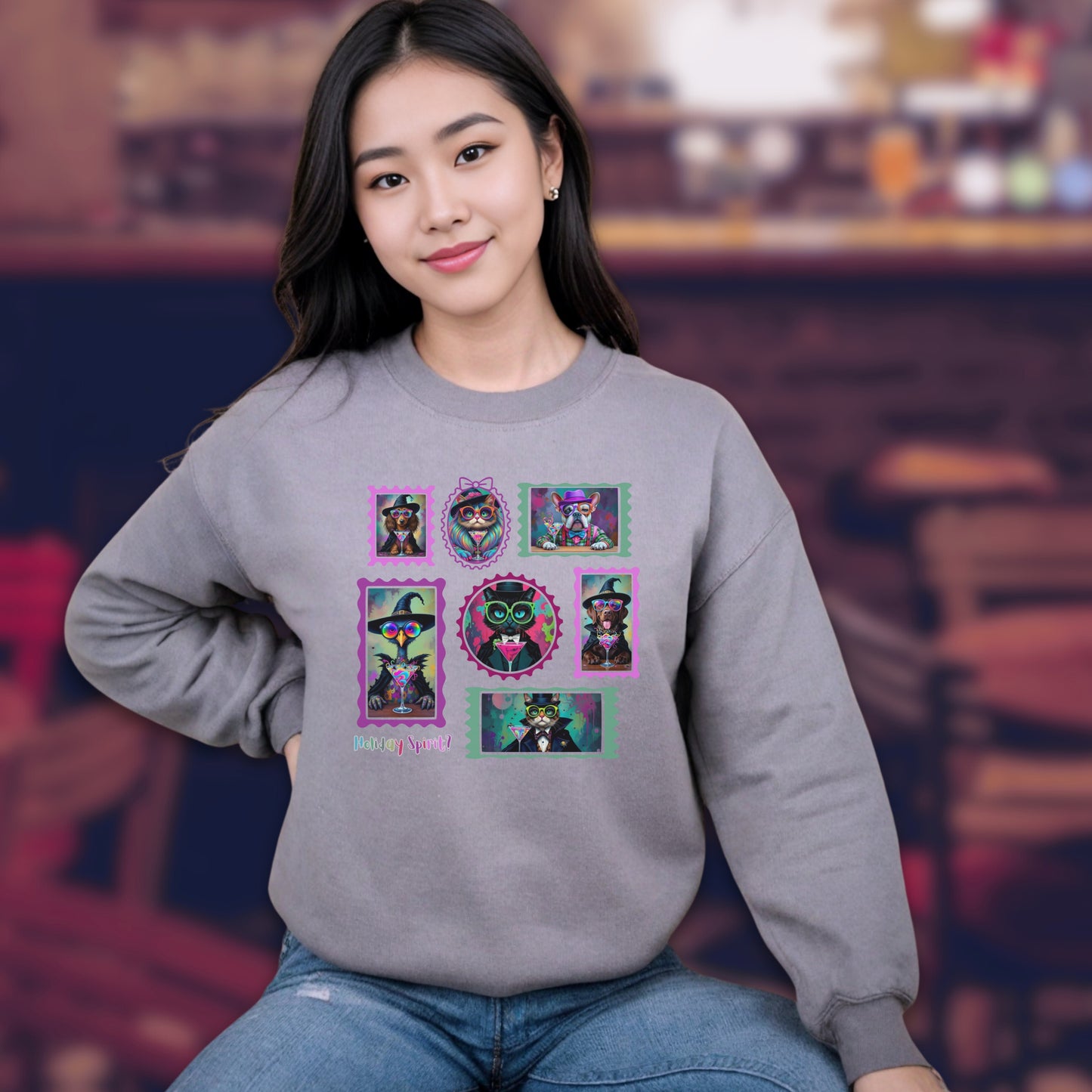 Young woman seated Sport Grey sweatshirt with colorful graphic design of Witchy cats and dogs and a spooky goose in hats and sun glasses drinking colorful cocktails on a blurred background of a pub.