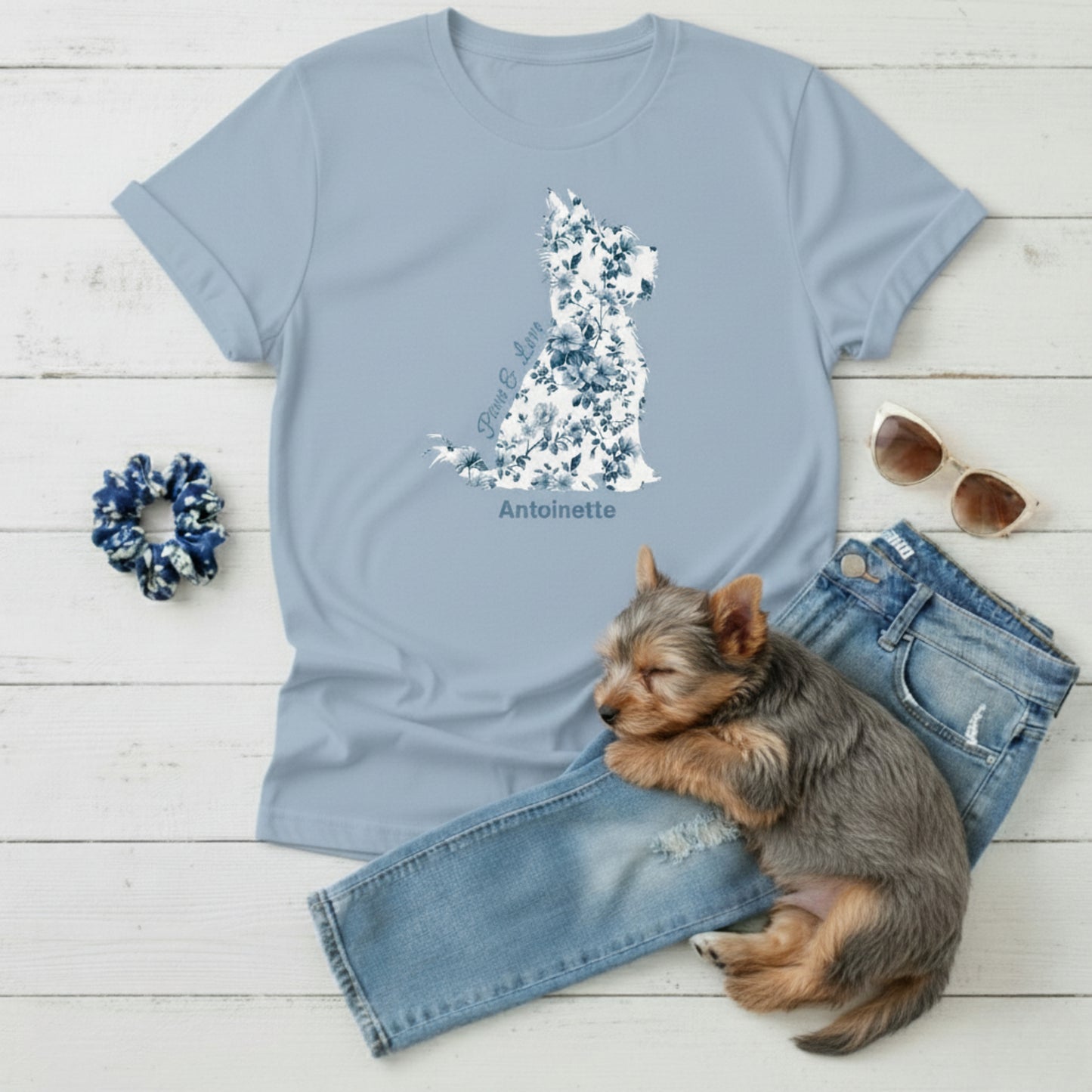 Flat lay of light blue Gildan 5000 t-shirt featuring blue Toile de Jouy Yorkshire Terrier silhouette with “Paws & Love” text; personalised Yorkie lover gift for her.