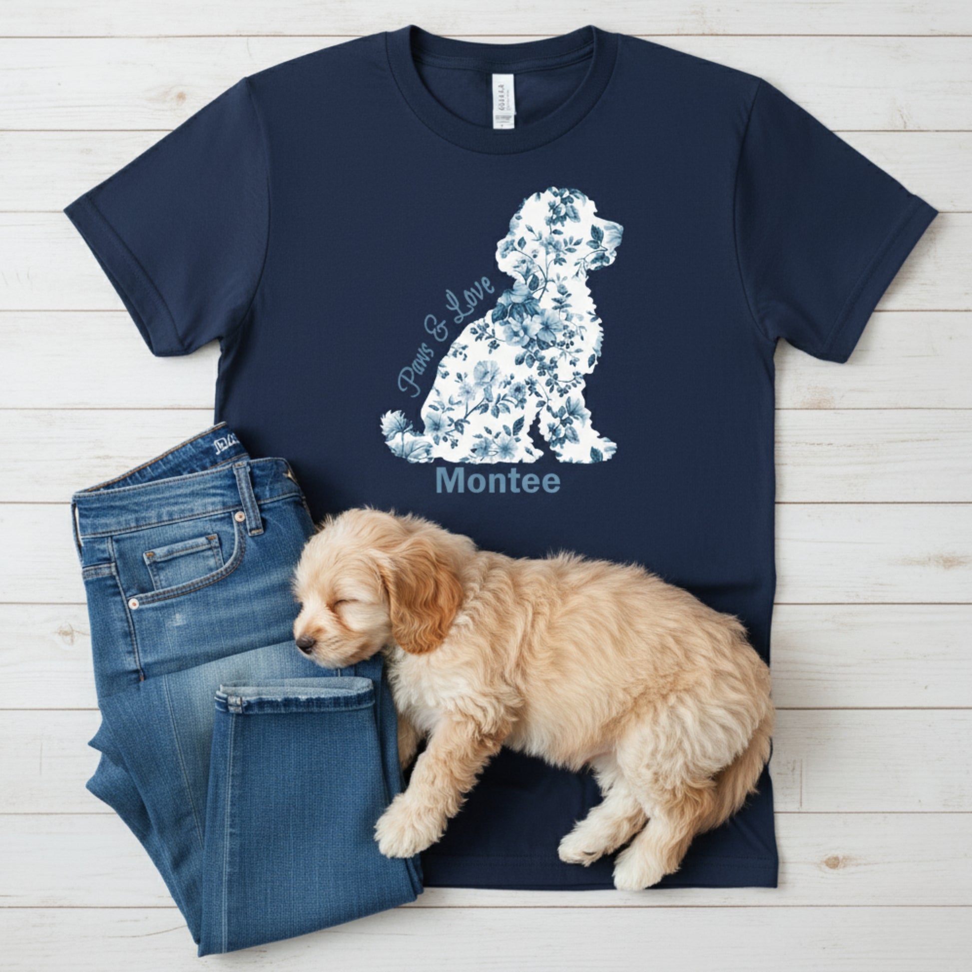Navy blue t-shirt with Cavapoo shaped French Coquette floral graphic and text, paired with jeans and a sleeping puppy on a wooden surface.