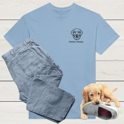 light blue t-shirt with custom embroidery of a dog and personalised text along with wardrobe suggestion of blue jeans on a wooden surface, with a puppy playing with a shoe in the background.