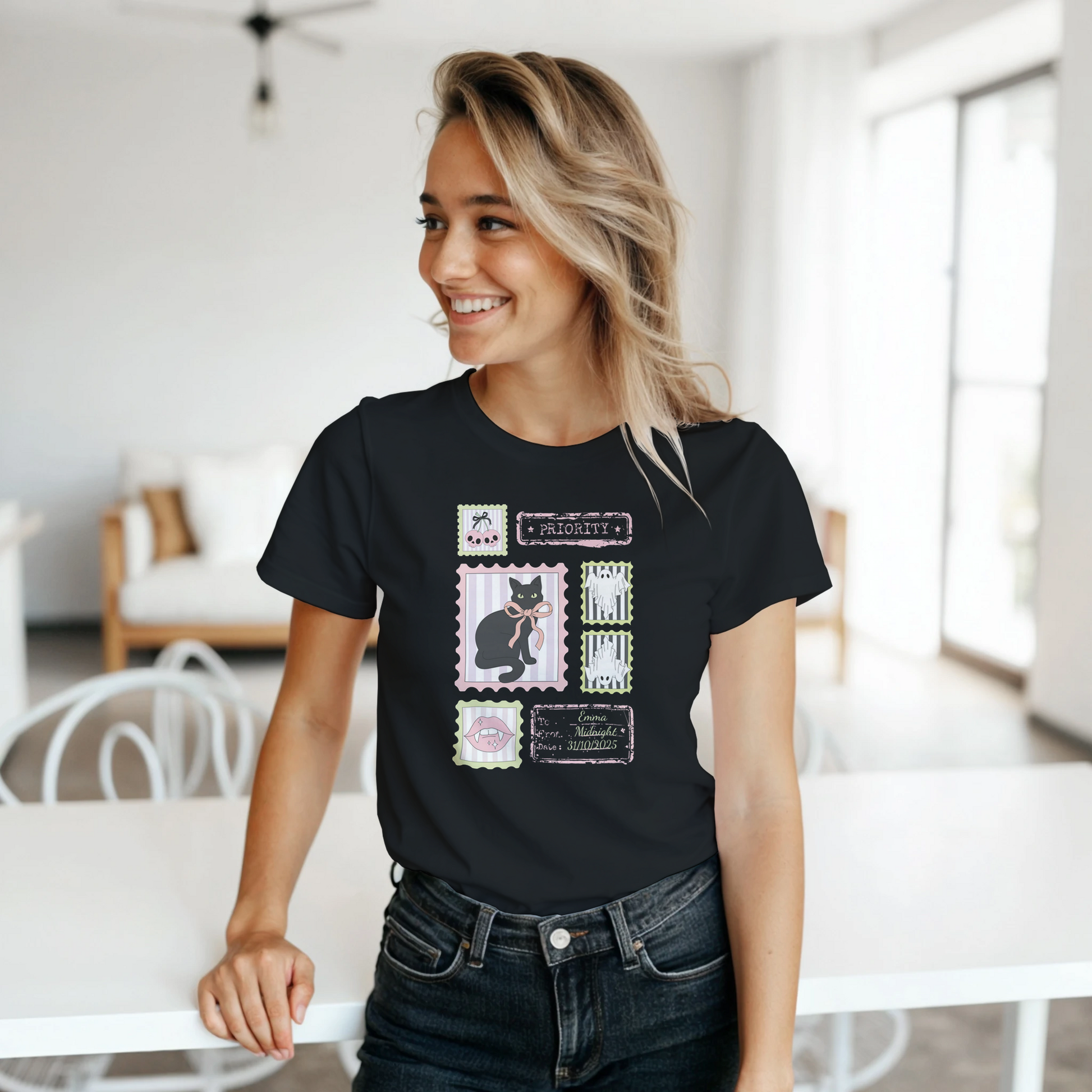Woman getting ready for spooky season wearing a cute black t-shirt with a Halloween collage graphic design, standing in a bright living area.