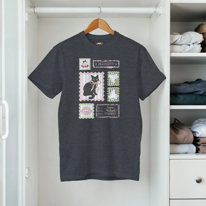 Hanging in a closet a gray t-shirt with a graphic retro stamps Halloween design that includes a black cat and bows.