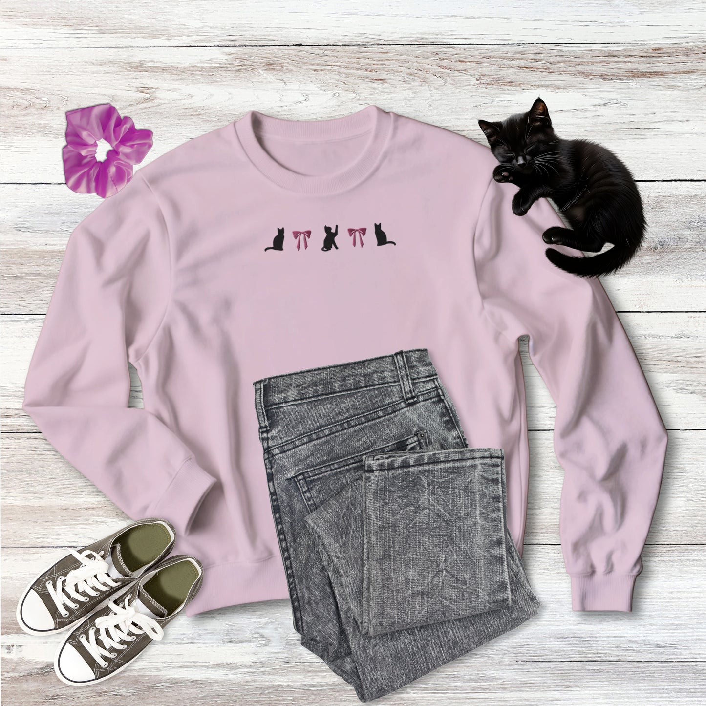 Embroidered Coquette Pink Bows and Black Cats on comfy medium weight Sweatshirt in light pink on wooden background with outfit style suggestion and sweet black kitten sleeping.