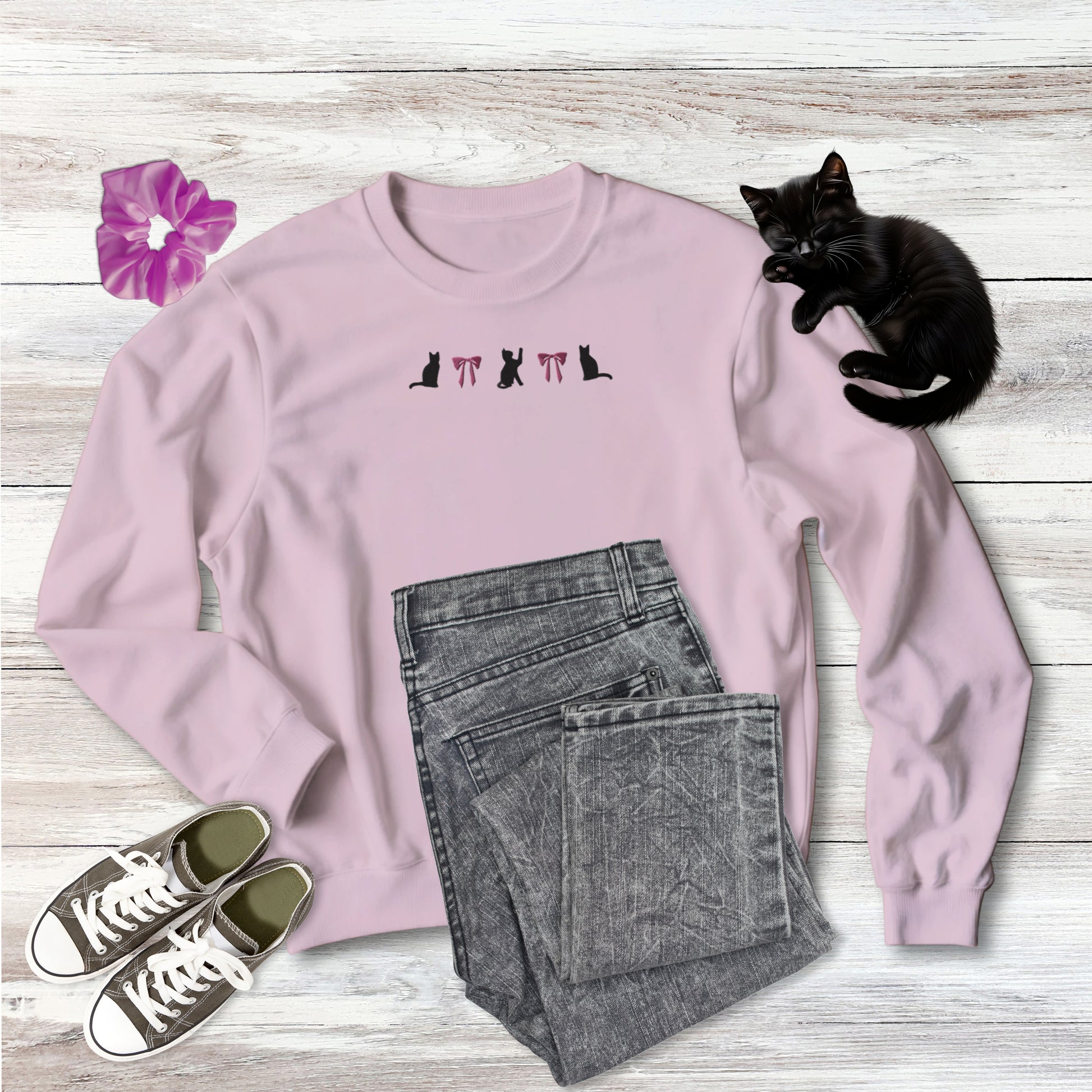 Embroidered Coquette Pink Bows and Black Cats on comfy medium weight Sweatshirt in light pink on wooden background with outfit style suggestion and sweet black kitten sleeping.