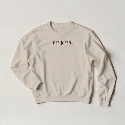 SAnd beige sweatshirt with black cats and pink bows embroidery across the front. The shirt is flat on a plain background.
