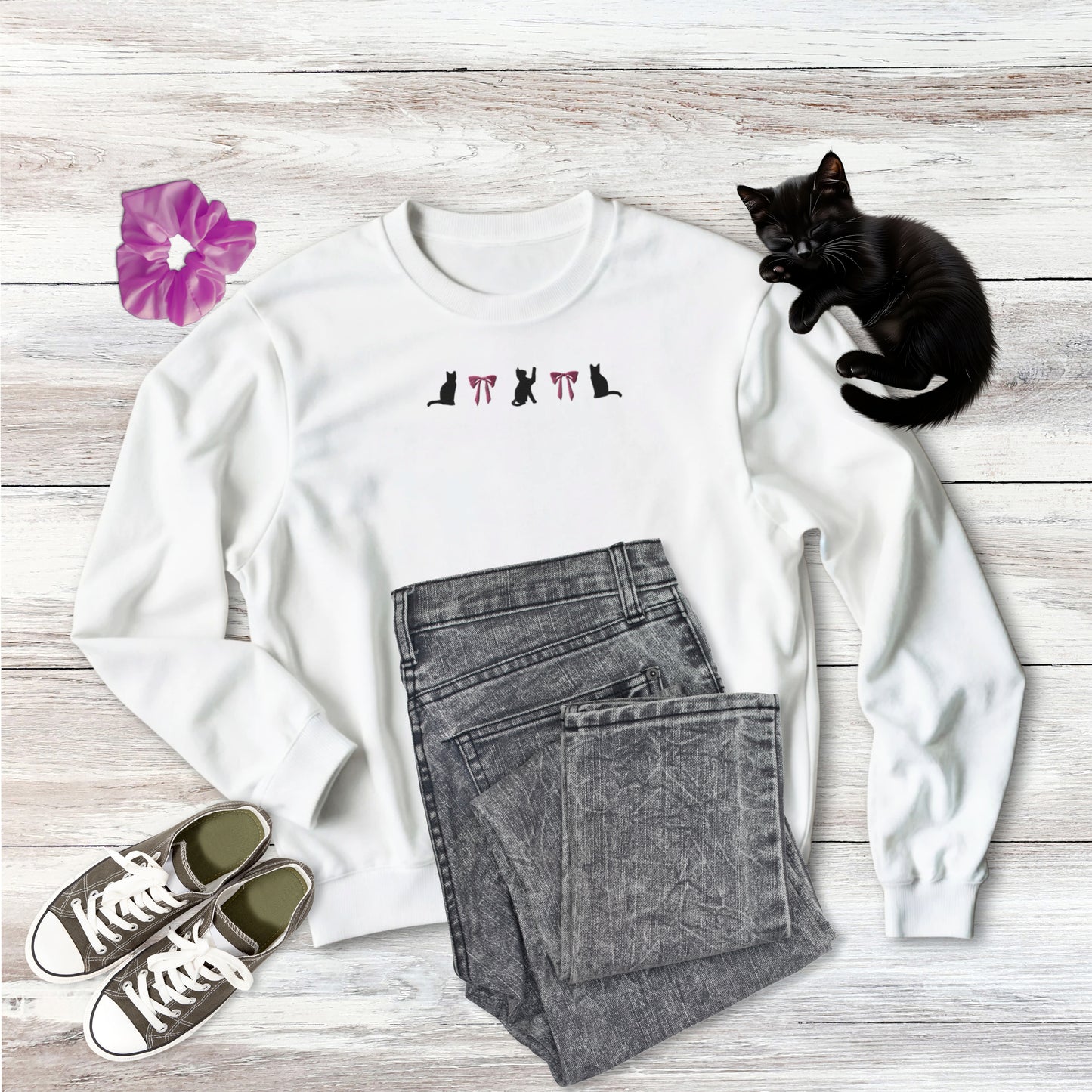 Embroidered Coquette Pink Bows and three Black Cats Halloween Gildan Sweatshirt in white on wooden background with outfit style suggestion and sweet black kitten sleeping.