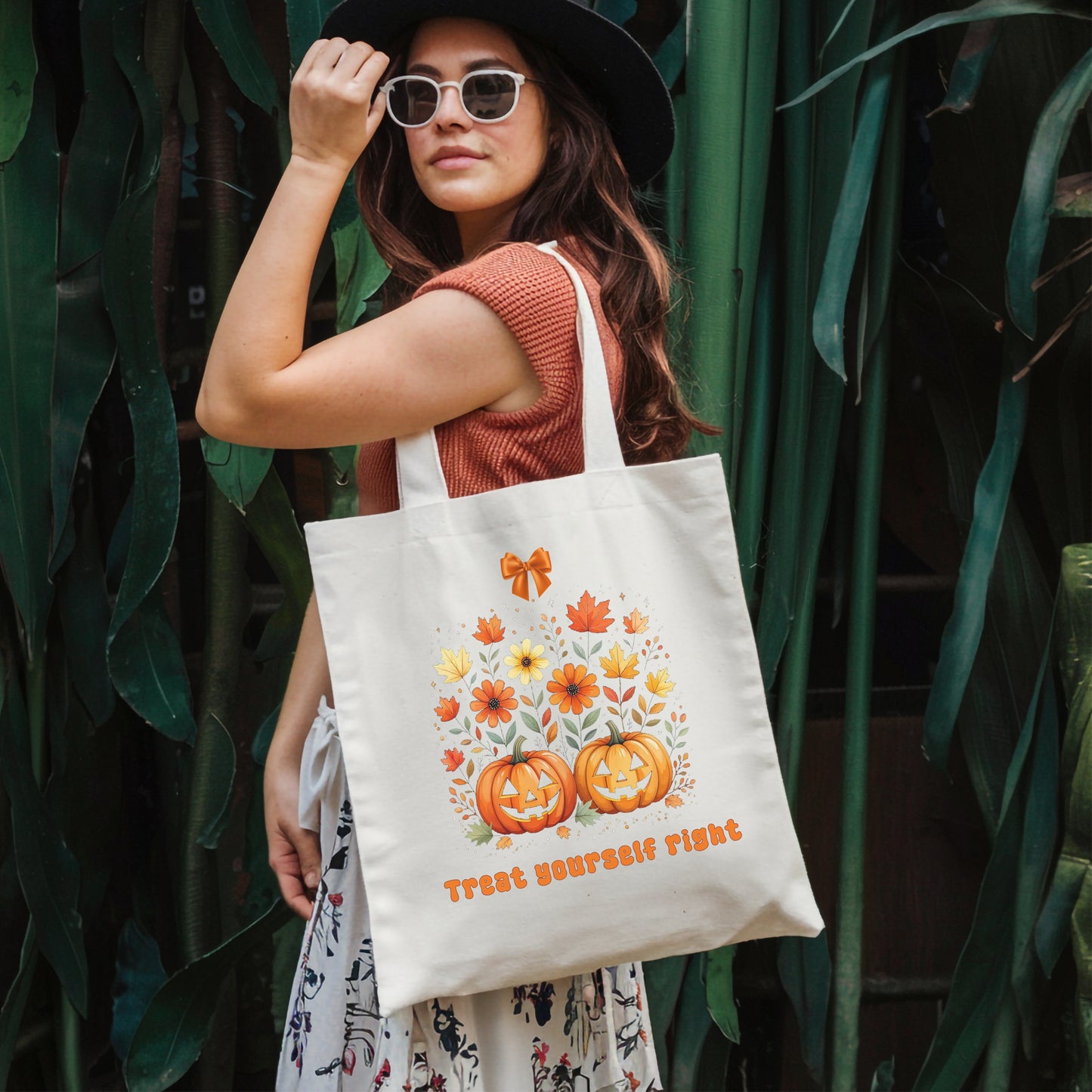 Woman holding a tote bag with Halloween-themed design against a green leafy background