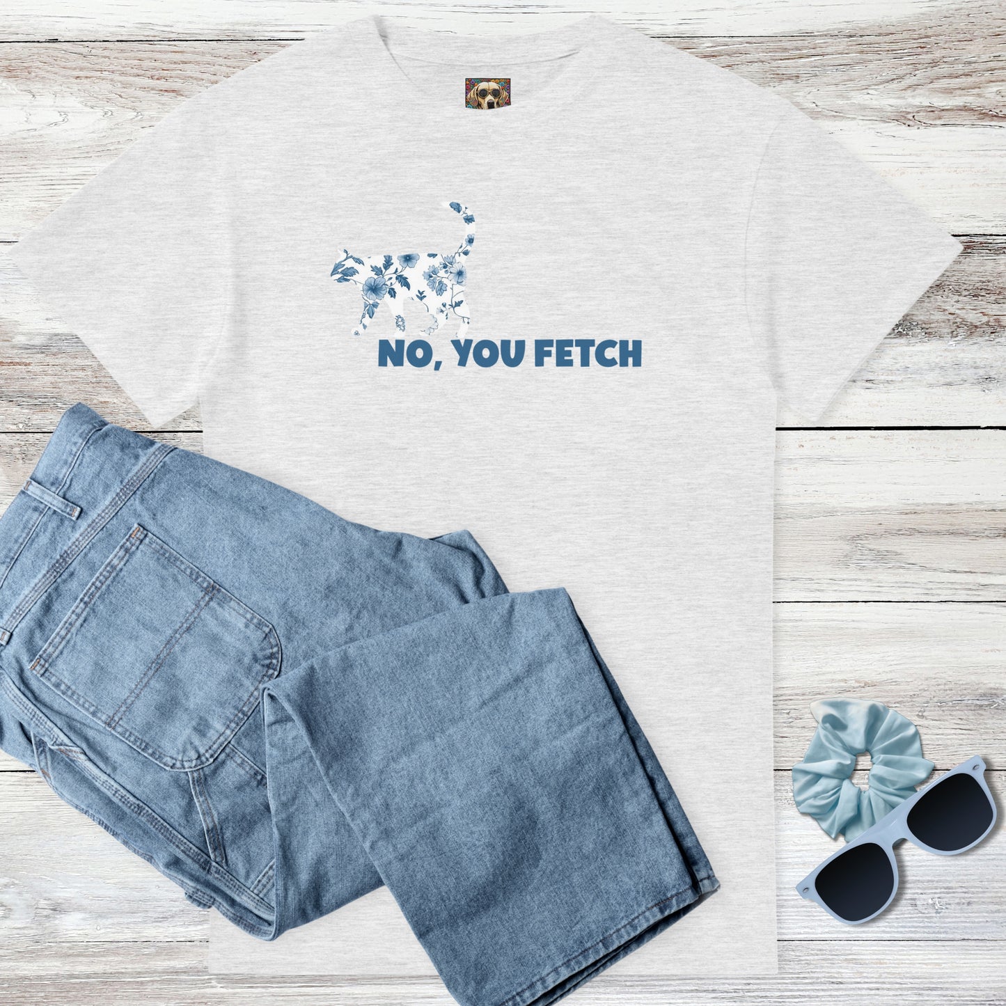 Ash grey coquette, toile de jouy on a cat t-shirt with witty 'NO, YOU FETCH' text, and outfit suggestion - blue jeans, sunglasses, and scrunchie on a wooden surface.