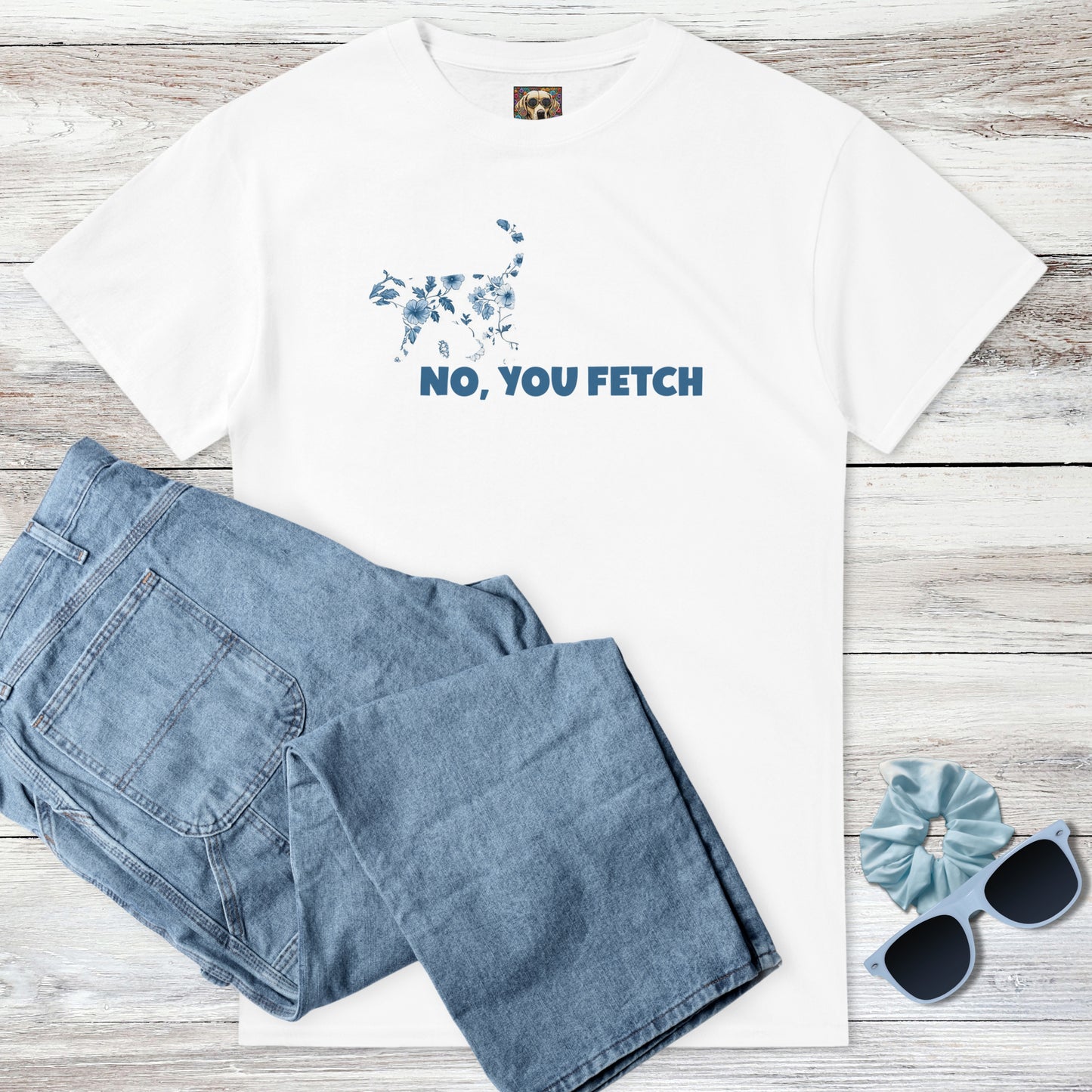 White tee with a coquette cottagecore blue and white flowers on a cat graphic above witty 'NO, YOU FETCH' text, and outfit suggestion - blue jeans, sunglasses, and scrunchie on a wooden surface.