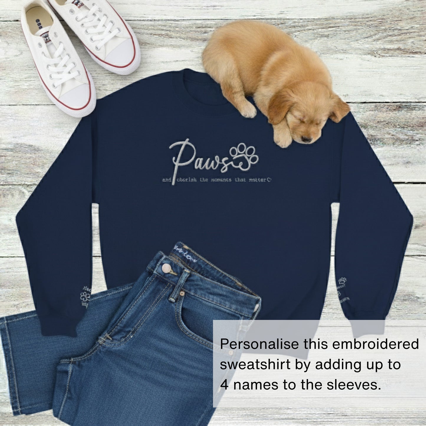 Embroidered, personalised crew neck pullover jumper in navy blue with wardrobe suggestion ofwhite trainers and a blue jeans.  Sleeping puppy is on top of the sweatshirt.