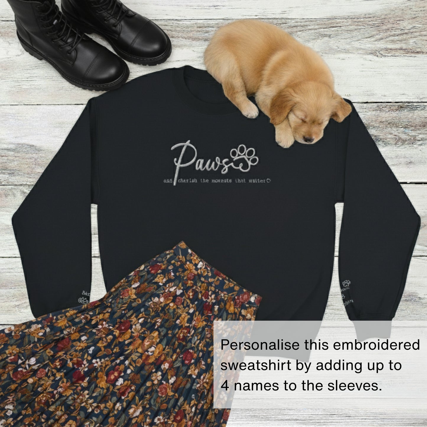 Embroidered, personalised crew neck pullover jumper in black with wardrobe suggestion of black boots and a floral skirt. Sleeping puppy is on top of the sweatshirt.