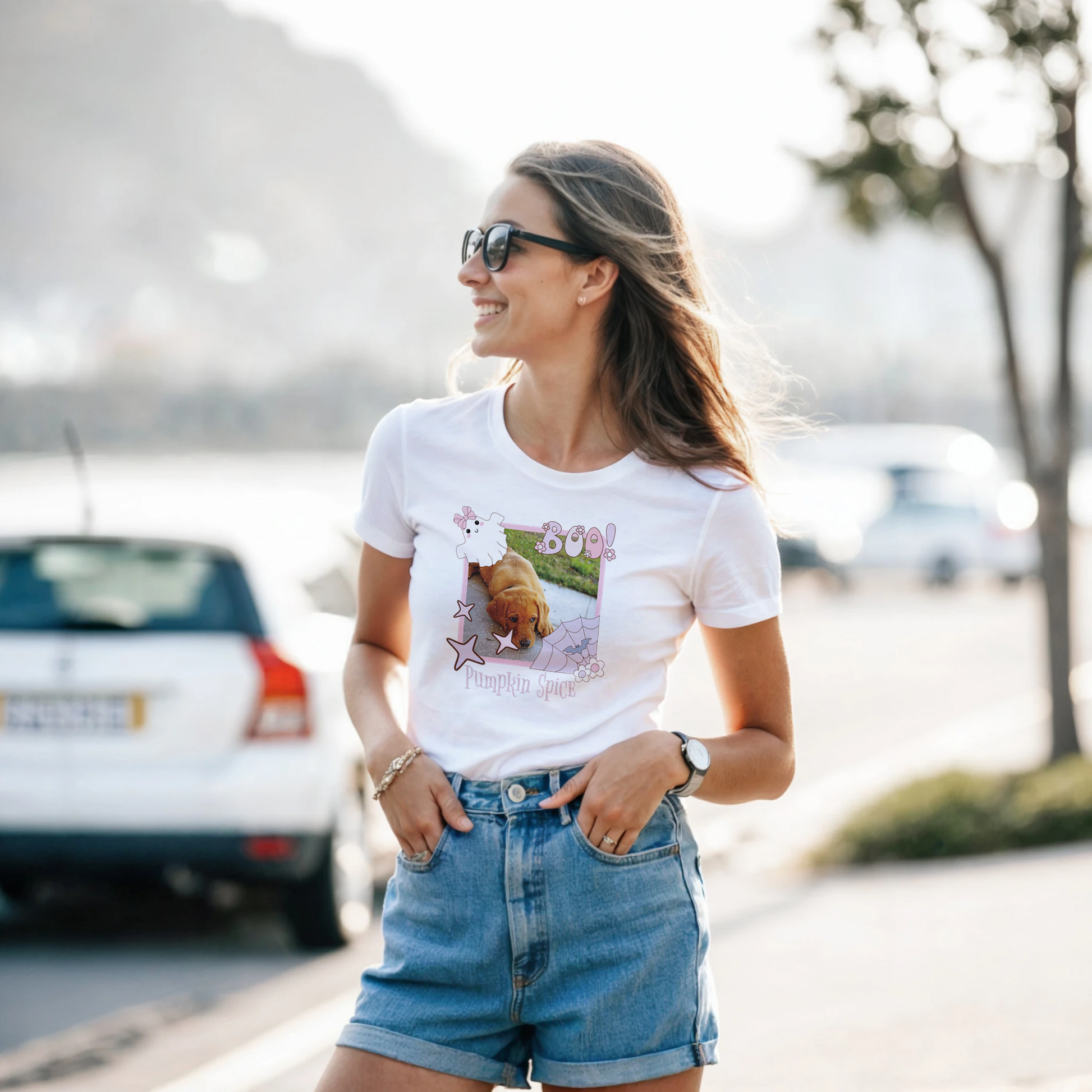 Woman wearing a white t-shirt with a Coquette pink Halloween picture frame graphic design standing outdoors