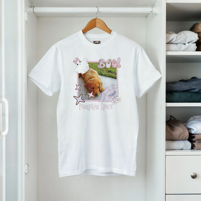 White t-shirt with a Coquette Pink Halloween picture frame graphic with a photo of a cute puppy inside it. Below is the  name, 'Pumpkin Spice in spooky font. The soft cotton tee is on a hanger in a closet.