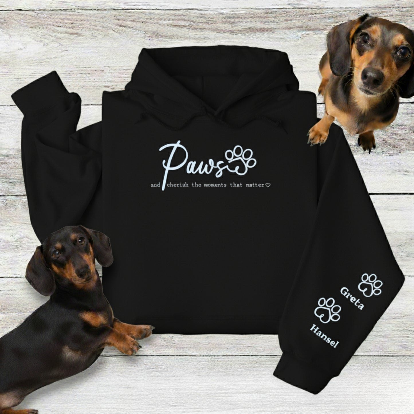 Personalise an embroidered black hooded sweatshirt with up to four pets' names shown with 2 Dachshunds on a wooden surface.