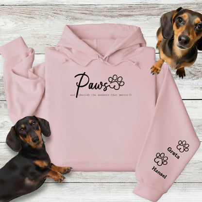 Light blue Gildan Hooded Sweatshirt with Custom Embroidery - up to 4 names on sleeves. Embroidery on the front of this shirt reads, 'Paws and cherish the moments that matter.' Flatlay with 2 Dachshunds