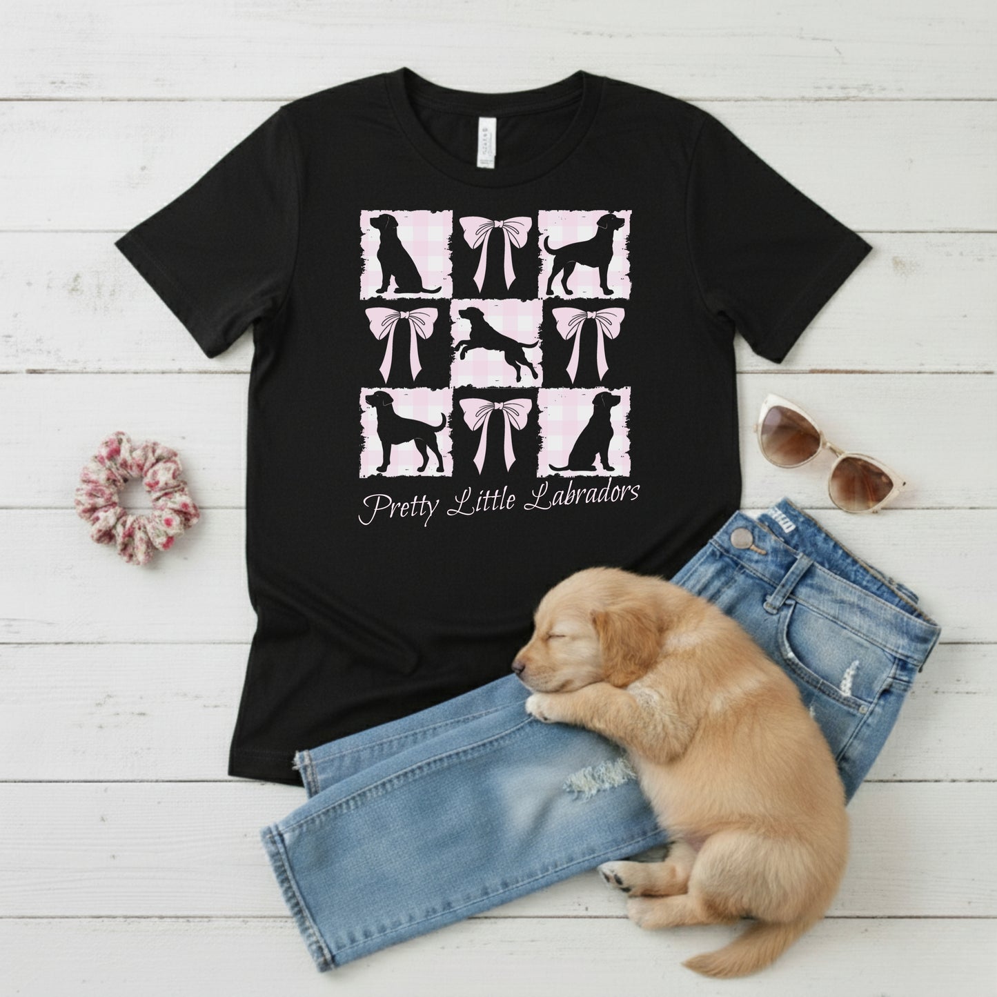  a Bella Canvas 3001 Black t-shirt with a Coquette Pink Bows & Checks Labrador Mum design flat lay with wardrobe suggestion and cute puppy. Custom Text choice - Pretty Little Labradors
