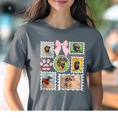 Woman wearing a dark grey t-shirt with colorful graphic designs of her dogs as postage stamps and a pink coquette bow. 