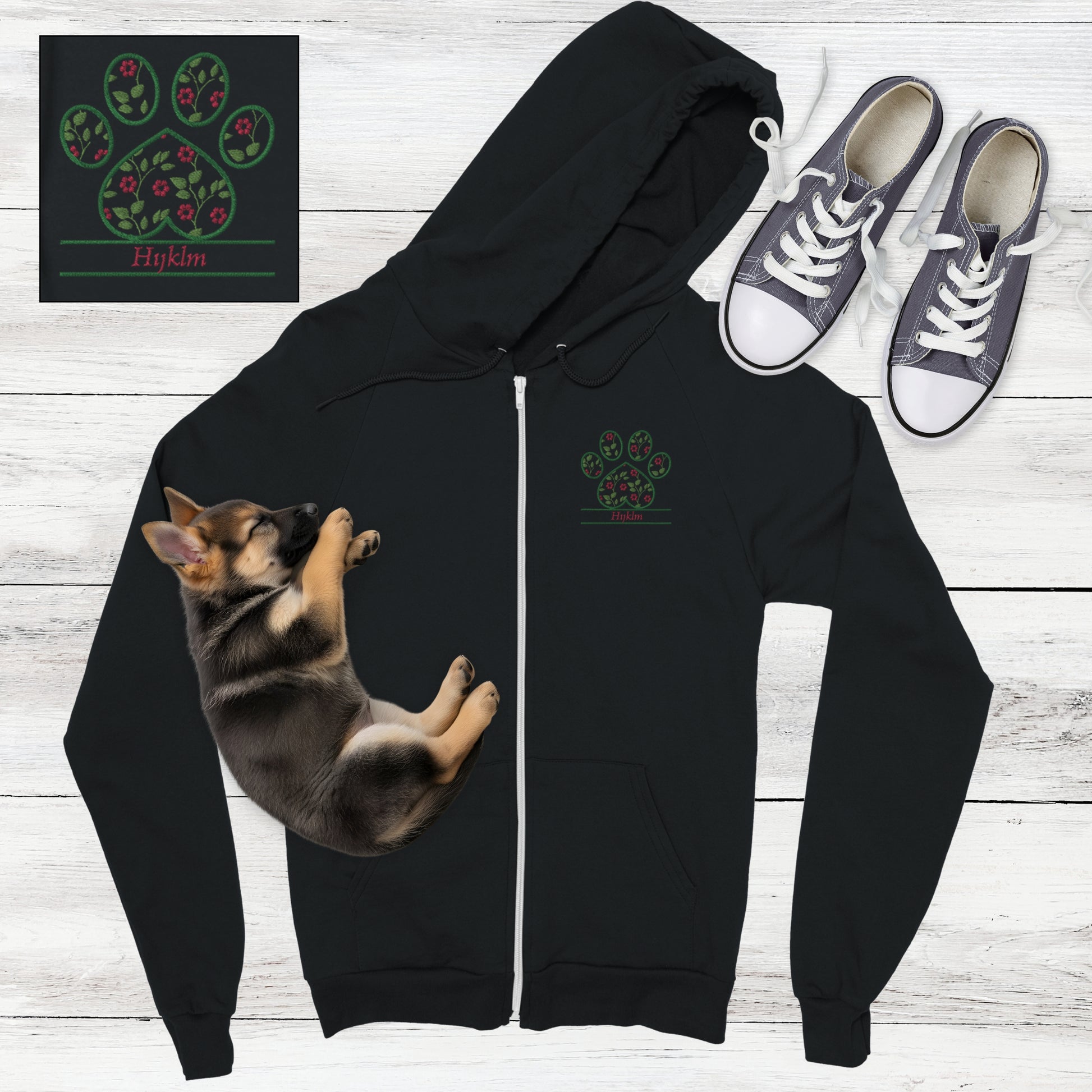 Black zip hoodie with pink cottagecore flowers embroidered inside a paw print with space for custom pet's name below - flat lay on wood with sleeping German Shepard puppy and sneakers