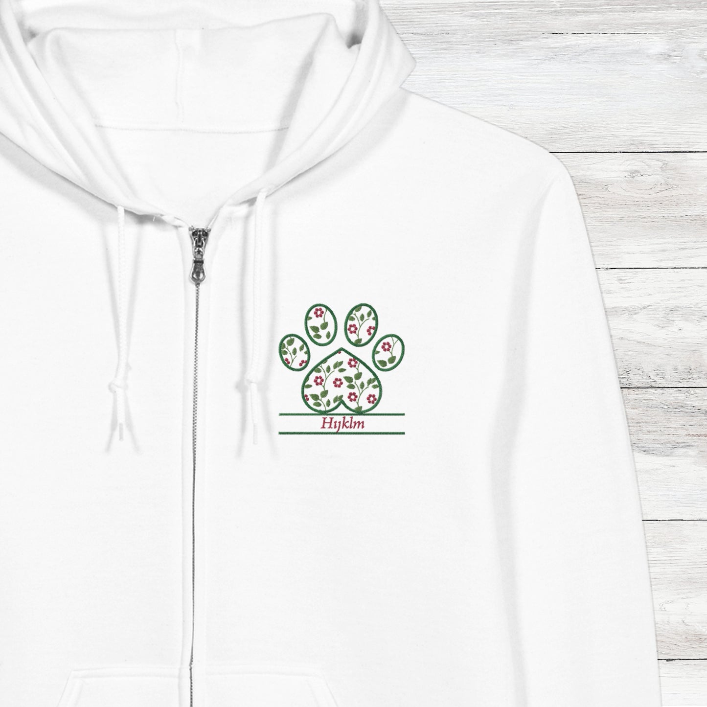 White hoodie with a embroidery floral paw print design close up with pet's name option on a wooden surface