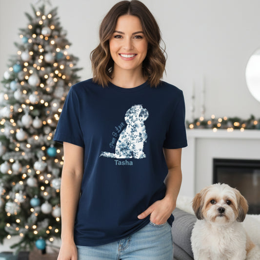 Woman wearing a navy blue t-shirt with a toile de jouy floral dog graphic and 'Paws & Love' text, standing in a room with a decorated Christmas tree and a Shih Tzu.