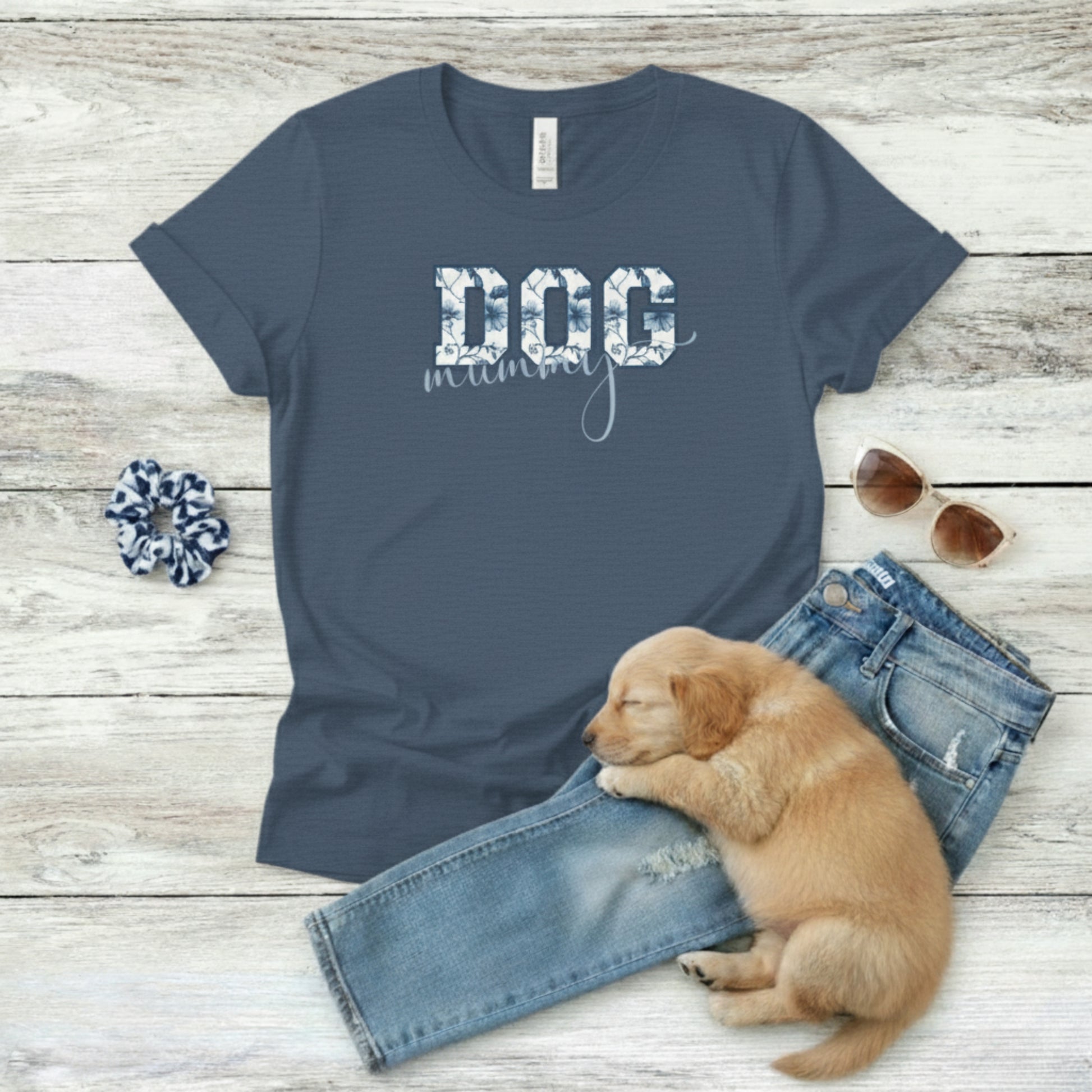 Navy blue t-shirt with 'DOG momma' text, puppy, jeans, scrunchie, and sunglasses on a wooden surface