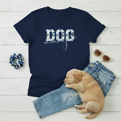 Navy blue Dog Mom t-shirt with 'DOG' text in Toile De Jouy print and mommy in script font. A cute puppy, scrunchie, sunglasses, and jeans on a light wooden surface suggest how to style this fitted tee.
