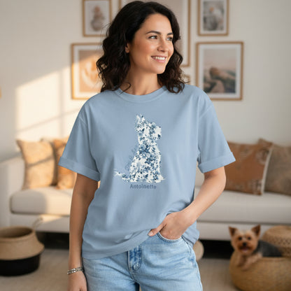 Woman in faded jeans wearing oversized Gildan 5000 light blue Yorkie Lover Tee with blue Toile de Jouy Yorkshire Terrier print; casual chic look in boho living room with Yorkie puppy in basket.